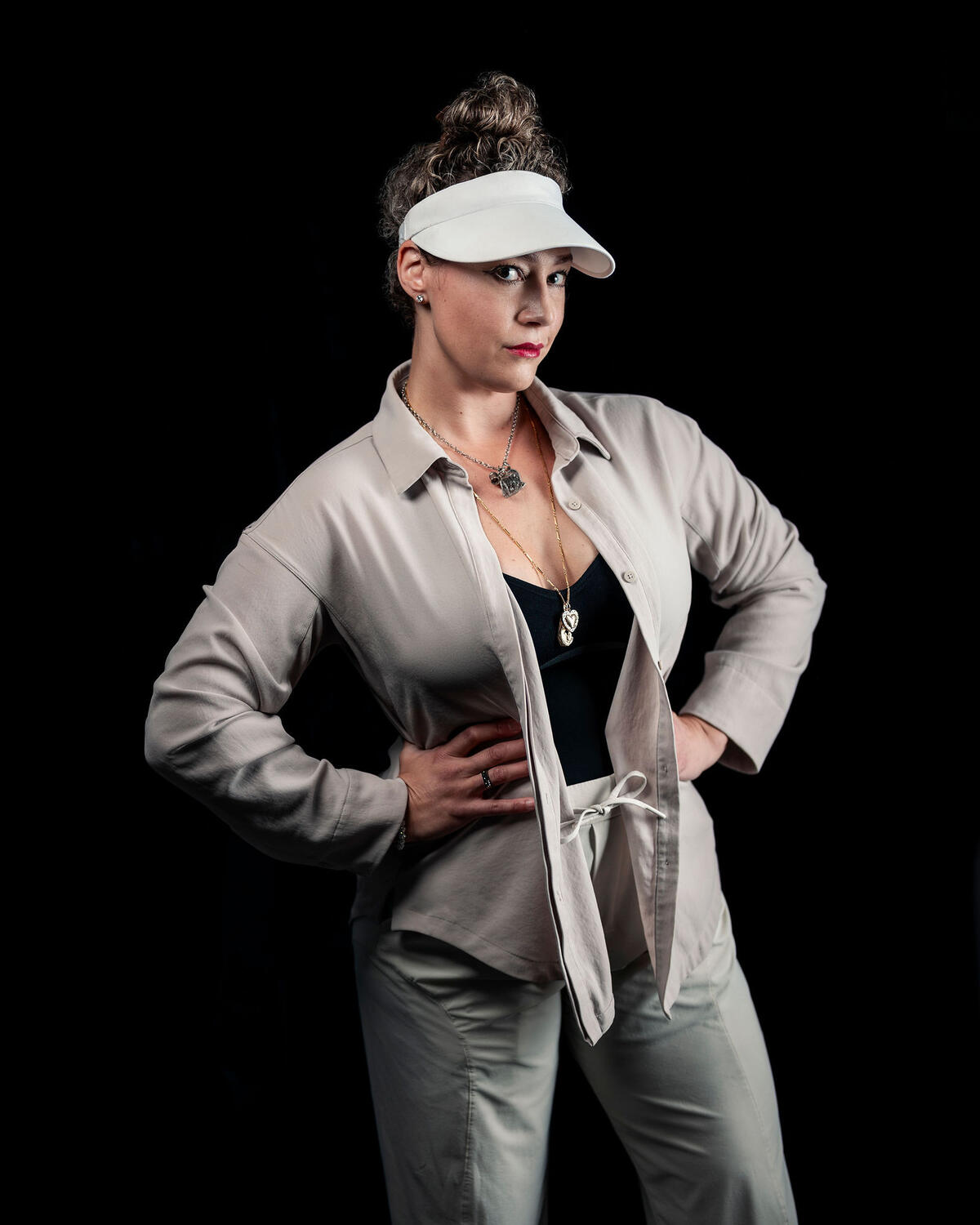 Amanda Kato in a white visor and a light suit, hands on her hips